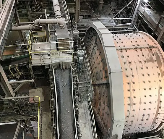 Technicien en équipement de protection soudant une structure métallique près d’un convoyeur industriel.