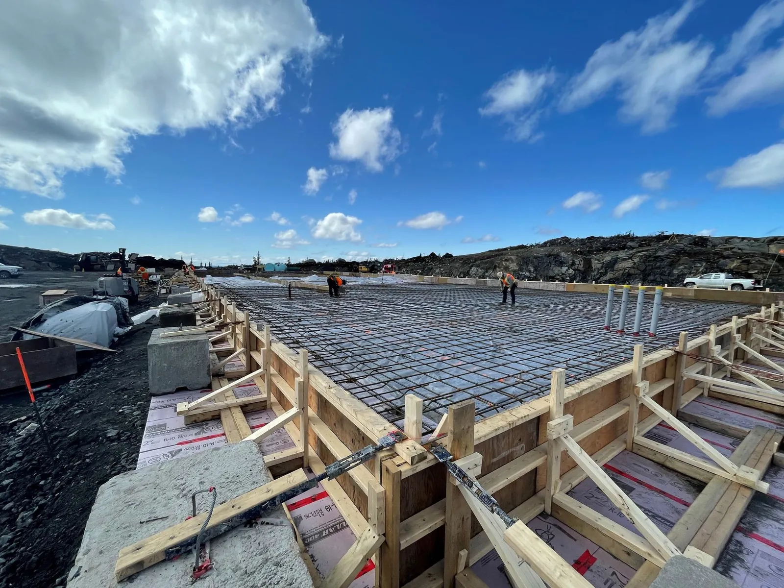 Ouvrier coulant et lissant une dalle de béton fraîche sur un chantier de génie civil.